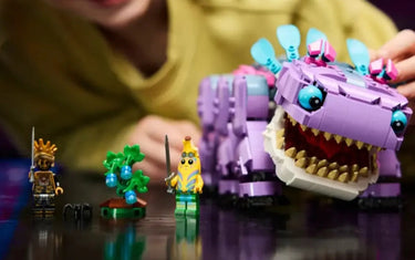 Child playing with colorful LEGO figures, including a purple monster and mini-figures on a table