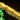 Close-up of a LEGO structure with bright yellow LED lights on beige and green bricks against black background