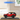 Red LEGO Ford Bronco SUV model in clear display case on wooden table, indoor setting