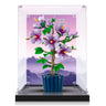 LEGO model of a purple flower plant in a blue pot displayed in a transparent protective case with mountain backdrop