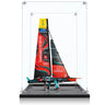 Detailed model of a racing sailboat with red and black sails in a clear display case