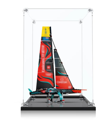 Detailed model of a racing sailboat with red and black sails in a clear display case