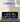 Blue LEGO Shelby Cobra 427 S/C model displayed in clear acrylic case on wooden surface