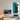 Modern workspace with iMac, desk lamp, smart speaker, and framed top view poster of a black Mercedes Formula 1 car