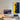 Modern minimalist workspace with desktop computer, racing car LEGO art on wall, desk lamp, and smart speaker
