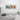 Minimalist living room with white sofa, checkered pillow, soft toy, and colorful Keith Haring style artwork on wall