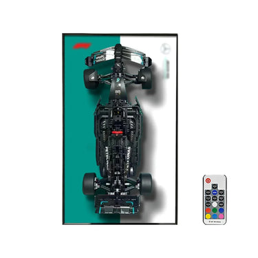 Top view of a black Petronas Formula 1 race car model with a split teal and white background and a remote control