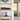 Red Formula 1 car model in display case on wooden shelf with potted plant and flower model below in modern room