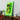 Yellow Lamborghini LEGO model mounted on green neon-lit wall display above wooden shelf with decor