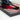 Close-up of a sleek black display stand with a blurred futuristic spaceship model on a red surface
