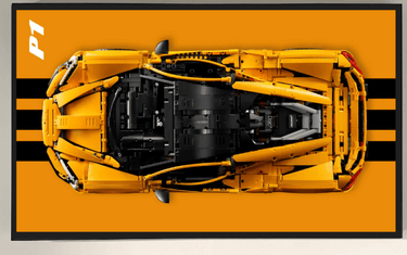 Top view of yellow LEGO sports car model on orange background with black racing stripes and P1 text