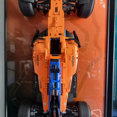 Top view of a LEGO McLaren Formula 1 race car model displayed on an orange plaque with McLaren branding