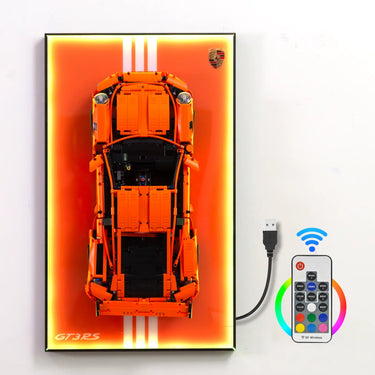 Orange GT3RS model car displayed on illuminated wall panel with white stripes and remote control