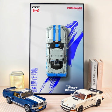 Lego model cars of Ford Mustang and Porsche 911 near a Nissan Skyline Fast and Furious framed poster