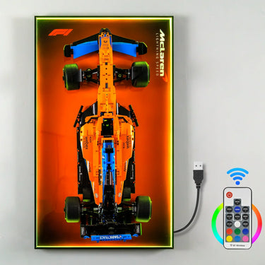 McLaren Formula 1 model car in orange with blue accents displayed on illuminated orange panel with remote control