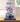 LEGO hibiscus flower model in blue pot displayed in clear protective case on wooden table