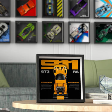 Framed yellow Porsche 911 GT3 RS model photo on wooden coffee table with car posters on wall