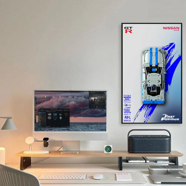 Modern minimalist desk setup with iMac, keyboard, lamp, smart speaker, and Fast and Furious Nissan GT-R poster