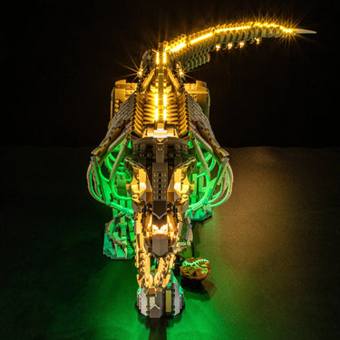 Illuminated LEGO dinosaur skeleton model with glowing yellow and green lights on black background