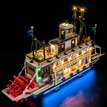 Illuminated LEGO paddle steamer ship model named Amelia with blue and green lights on black background