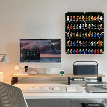 Modern workspace with desktop, wireless keyboard, mouse, speaker, and wall-mounted display case of Lego minifigures