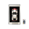 Framed white model Porsche 911 car with red roof and black base displayed on black background with remote control