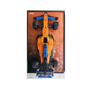 Top view of a detailed McLaren Formula 1 car model in orange and blue on a branded display board